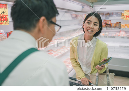 A female customer is seen smiling broadly while talking to a store clerk in the meat section of a supermarket. A female customer is seen smiling broadly while talking to a store clerk in the meat section of a supermarket. 140752259