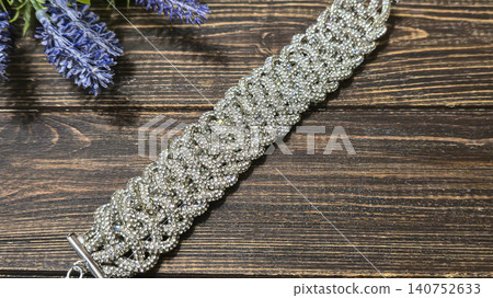 A bracelet made of shiny cords on a dark background. Women's jewelry. Handmade. A bracelet made of shiny cords on a dark background. Women's jewelry. Handmade. 140752633
