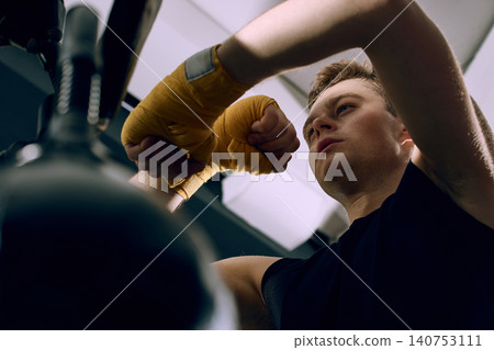 Close up of boxer with hand wraps training punches on reflex bag. Close up of boxer with hand wraps training punches on reflex bag. 140753111