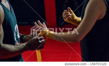 Close up of coach wrapping boxer hands with yellow protective bandage. 140753126