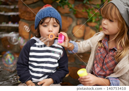 Boy, girl and playing with bubbles, outdoors and garden in winter season. Bonding, love and sister with brother blowing for fun and entertainment, family and youth in nature with soap bubble 140753410