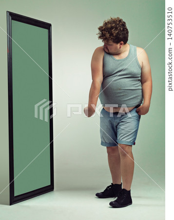 Man, flex and body image in mirror for eating disorder, anxiety and mental health. Depression, weight gain and insecurity for plus size male person, reflection and muscle and frustrated or sad Man, flex and body image in mirror for eating disorder, anxiety and mental health. Depression, weight gain and insecurity for plus size male person, reflection and muscle and frustrated or sad 140753510