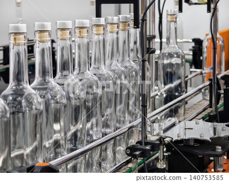 Bottles move along a production line in a factory during the daytime while being prepared for filling and packaging Bottles move along a production line in a factory during the daytime while being prepared for filling and packaging 140753585