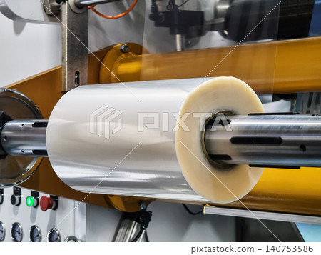 Machine rolls film in a production line at a factory Machine rolls film in a production line at a factory 140753586