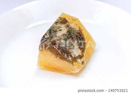 Piece of amber resin with dark inclusions on a white plate in a well lit setting Piece of amber resin with dark inclusions on a white plate in a well lit setting 140753821