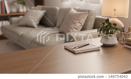 Close up of wooden table with notebook and potted plant beside grey sofa in cosy modern living room. Close up of wooden table with notebook and potted plant beside grey sofa in cosy modern living room. 140754042