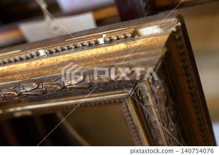 Detailed View of a Vintage Wooden Frame With Intricate Carvings and Gold Accents in an Art Shop Setting 140754076