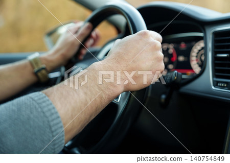 Male hands holding steering wheel while driving Male hands holding steering wheel while driving 140754849