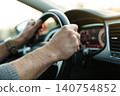 Male hands holding steering wheel while driving 140754852