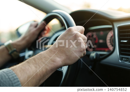 Male hands holding steering wheel while driving Male hands holding steering wheel while driving 140754852