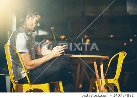 Man, laptop and relax with phone at cafe for social media, communication or networking at indoor restaurant. Male person sitting on mobile smartphone for online chatting or texting at coffee shop 140754881