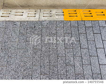 Interlocking paving blocks and yellow drainage groove textures covering city sidewalks Interlocking paving blocks and yellow drainage groove textures covering city sidewalks 140755548