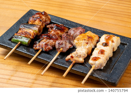 A juicy assortment of grilled chicken skewers, with the aroma of charcoal grilling that will whet your appetite. 140755794