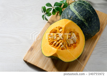 A fresh pumpkin placed on a wooden cutting board. A fresh pumpkin placed on a wooden cutting board. 140755972