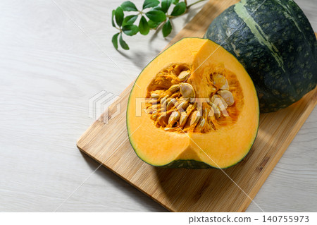 A fresh pumpkin placed on a wooden cutting board. A fresh pumpkin placed on a wooden cutting board. 140755973
