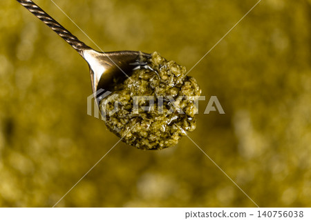 Spoonful of traditional green basil pesto sauce close up Spoonful of traditional green basil pesto sauce close up 140756038