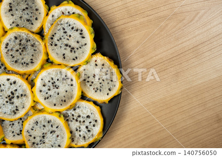 Sliced yellow dragon fruit on black plate with copy space Sliced yellow dragon fruit on black plate with copy space 140756050