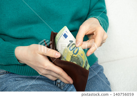 Hands put the euro banknotes in the wallet. Concepts of financial security, liquidity, and economic stability with paper currency Hands put the euro banknotes in the wallet. Concepts of financial security, liquidity, and economic stability with paper currency 140756059