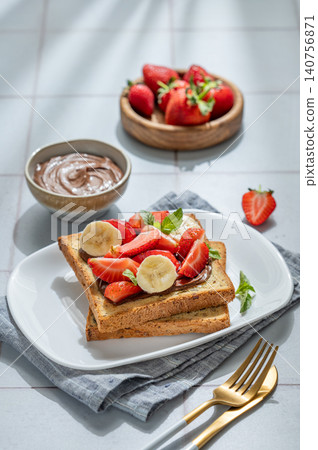 Toasted bread with chocolate cream, strawberries, and banana on a plate on a tile background Toasted bread with chocolate cream, strawberries, and banana on a plate on a tile background 140756871