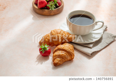 Baked croissants, cup of espresso coffee and strawberries on a bright textured background. 140756891