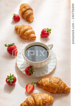 Baked croissants, cup of espresso coffee and strawberries on a bright textured background. Baked croissants, cup of espresso coffee and strawberries on a bright textured background. 140756894