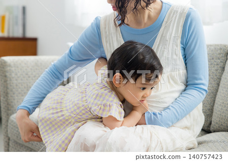 A pregnant mother holding her one-year-old daughter. A pregnant mother holding her one-year-old daughter. 140757423