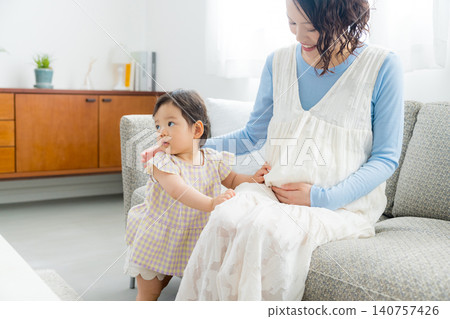 A pregnant mother holding her one-year-old daughter. 140757426