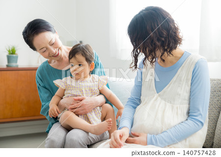 一位懷孕的母親抱著她一歲的女兒。 一位懷孕的母親抱著她一歲的女兒。 140757428