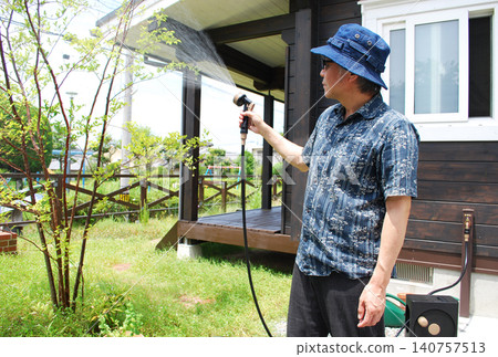 A man waters his garden in the summer. A man waters his garden in the summer. 140757513