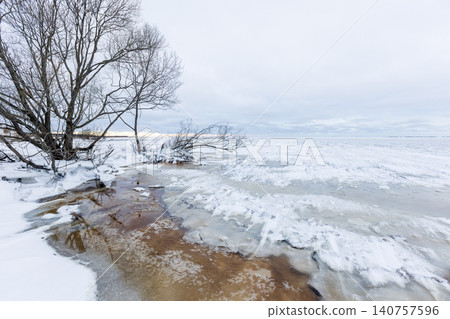 A quiet winter shoreline featuring bare trees, frozen Baltic Sea A quiet winter shoreline featuring bare trees, frozen Baltic Sea 140757596