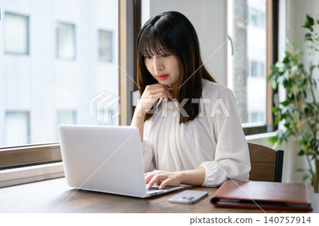 在辦公室使用筆記型電腦的年輕女商人 在辦公室使用筆記型電腦的年輕女商人 140757914