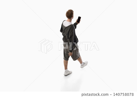 Young man showing smartphone screen while walking isolated on white background. Young man showing smartphone screen while walking isolated on white background. 140758078