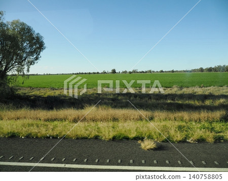 The scenery from the car window—farmland stretching along the road—the contrast between the dry roadside and the green leaves creates a unique look for the journey. 140758805