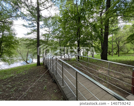Wooded park with metal ramp and lush green trees, suitable for nature background or copy space Wooded park with metal ramp and lush green trees, suitable for nature background or copy space 140759242