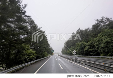 雨後的高速公路:道路被濕漉漉的路面和霧氣籠罩。 雨後的高速公路:道路被濕漉漉的路面和霧氣籠罩。 140759445
