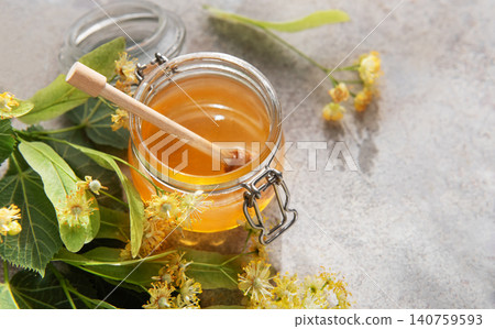 Honey jar with linden blossoms and wooden dipper Honey jar with linden blossoms and wooden dipper 140759593