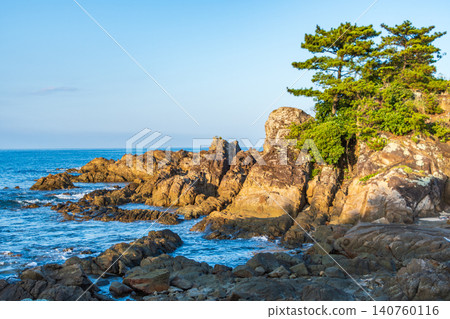 夕陽西下,映照著嶙峋的岩石峭壁和蒼翠的松樹,構成了一幅令人驚嘆的海岸風光。 夕陽西下,映照著嶙峋的岩石峭壁和蒼翠的松樹,構成了一幅令人驚嘆的海岸風光。 140760116