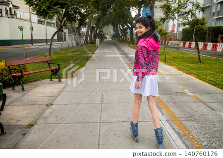 Happy Young Girl Rollerblading and Smiling at Camera Happy Young Girl Rollerblading and Smiling at Camera 140760176