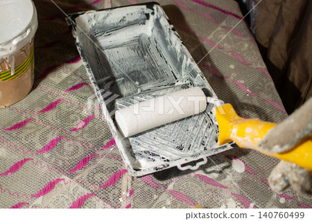 Hand dipping roller into paint tray. Self made home improvement on budget. Cosmetic renovation Hand dipping roller into paint tray. Self made home improvement on budget. Cosmetic renovation 140760499