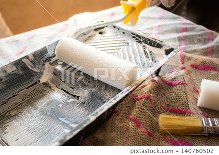 Hand dipping roller into paint tray. Spring home refresh. Budget friendly transformation. Small improvements, big mood boost. Smart spending 140760502