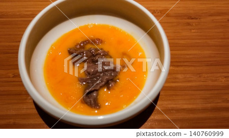 close up of Japanese Sukiyaki hot pot wagyu beef slice in a rich orange raw egg yolk broth sauce in a white bowl on a wooden table with copy space close up of Japanese Sukiyaki hot pot wagyu beef slice in a rich orange raw egg yolk broth sauce in a white bowl on a wooden table with copy space 140760999