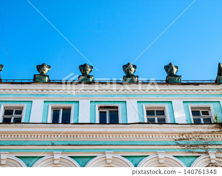 Row of baroque vases on a building roof cornice during facade restoration with green netting Row of baroque vases on a building roof cornice during facade restoration with green netting 140761348