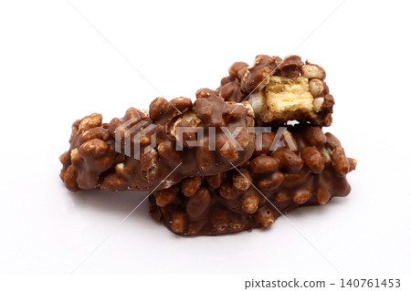 Chocolate-coated cereal clusters, one broken open. Golden center contrasts with dark, textured exterior. Simple white background highlights snack's rich appeal. Perfect for food blogs, recipes Chocolate-coated cereal clusters, one broken open. Golden center contrasts with dark, textured exterior. Simple white background highlights snack's rich appeal. Perfect for food blogs, recipes 140761453