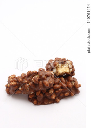 Chocolate-coated cereal clusters, one broken open. Golden center contrasts with dark, textured exterior. Simple white background highlights snack's rich appeal. Perfect for food blogs, recipes Chocolate-coated cereal clusters, one broken open. Golden center contrasts with dark, textured exterior. Simple white background highlights snack's rich appeal. Perfect for food blogs, recipes 140761454