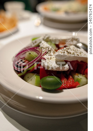 Fresh Greek salad with cucumbers, tomatoes, olives, onions, and feta cheese in a white bowl Fresh Greek salad with cucumbers, tomatoes, olives, onions, and feta cheese in a white bowl 140761474