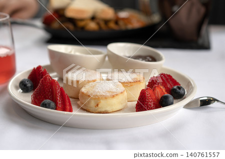 Freshly baked scones with strawberries, blueberries, and sauces served on a white plate at a restaurant Freshly baked scones with strawberries, blueberries, and sauces served on a white plate at a restaurant 140761557