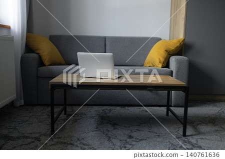 Open laptop on coffee table in modern living room interior without people Open laptop on coffee table in modern living room interior without people 140761636