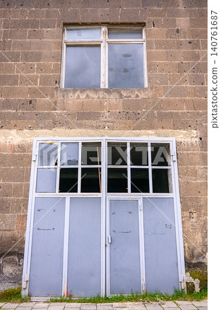 Weathered industrial-style facade with two windows showing damage Weathered industrial-style facade with two windows showing damage 140761687