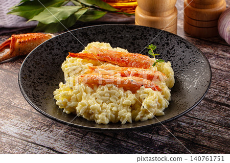 Creamy risotto with crab claws in dark speckled bowl on rustic wood Creamy risotto with crab claws in dark speckled bowl on rustic wood 140761751