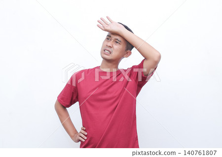 Man shrugs, hands open, showing uncertainty. He wears a simple red tshirt. His expression suggests confusion or indifference. Ideal for situations requiring a gesture of hesitation Man shrugs, hands open, showing uncertainty. He wears a simple red tshirt. His expression suggests confusion or indifference. Ideal for situations requiring a gesture of hesitation 140761807